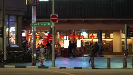 Toma-Estática-De-Cerca-Que-Captura-El-Tráfico-Nocturno-Y-El-Restaurante-En-La-Esquina-De-New-Bridge-Road-Y-Upper-Cross-Street-En-El-Centro-Comercial-Chinatown-Point,-Singapur