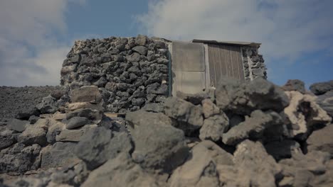 Dolly-shot-of-house-built-with-volcanic-rocks-on-an-island