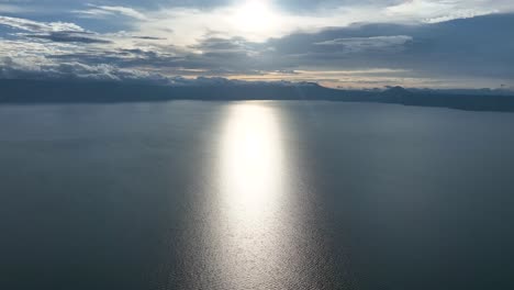 Sunset-reflecting-on-Lake-Toba-with-clouds-and-distant-mountains,-serene-mood