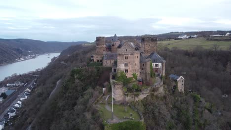 Aerial-toward-medieval-Schoenburg-Castle-hotel-atop-hillside-overlooking-Rhine