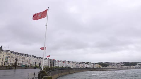 Douglas-City-Promenade-An-Bewölktem-Tag,-Staatsflaggen-Und-Gebäude-Am-Wasser,-Zeitlupe