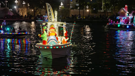 Gente-Divirtiéndose-Y-Celebrando-Las-Fiestas-Y-Disfrazados-De-Santa-Y-Elfo-En-Un-Bote-Flotante-En-El-Desfile-De-Botes-De-Navidad-En-Tampa,-Florida,-Toma-Nocturna