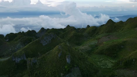 Lush-green-hills-of-Osmena-Peak-under-a-dramatic-sky-at-dusk,-aerial-view