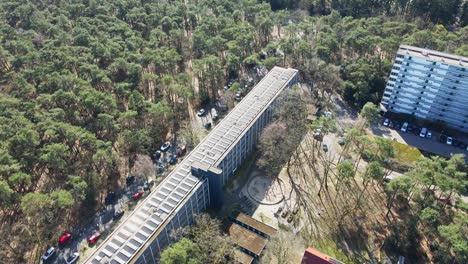 Aerial-of-a-beautiful-apartment-building-with-a-rooftop-filled-with-photovoltaic-solar-panels-on-a-sunny-day---drone-flying-backwards