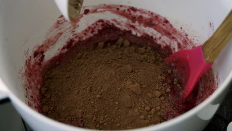 Adding-chocolate-cocoa-powder-into-red-beets-muffin-batter-inside-a-white-bowl-to-make-valentine's-day-muffins