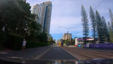 Punto-De-Vista-Conduciendo-A-Través-Del-Paraíso-De-Los-Surfistas-Pasando-Un-Tranvía,-Gold-Coast