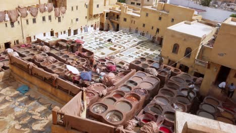 Panoramic-view-of-the-Chouara-Tannery-in-Fez,-the-workers-preparing-and-coloring-the-quality-leathers-in-Morocco