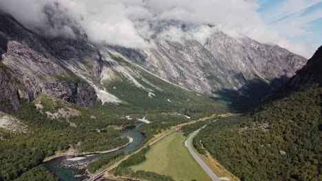 Aerial-footage-showing-the-Rauma-river-in-Norway,-with-mountains,-greenery-and-grass