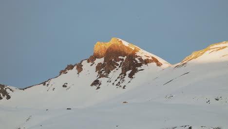 Mit-Einer-Drohne-Aufgenommene-Luftaufnahme-Des-Sonnenaufgangs,-Die-Die-Majestätische-Silhouette-Einer-Schneebedeckten-Bergkette-Offenbart