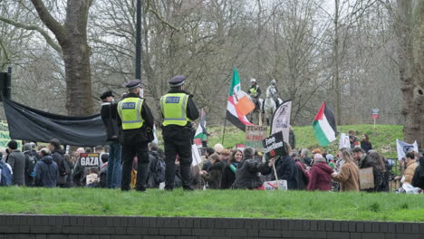 Die-Berittene-Londoner-Polizei-Beaufsichtigt-Demonstranten-Mit-Palästinensischen-Flaggen-Und-Bannern,-Die-Im-Zentrum-Londons-Die-Straßen-Entlang-Marschieren