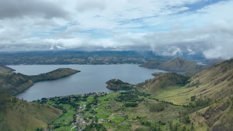 Lush-greenery-of-Samosir-Island-with-Lake-Toba-in-the-backdrop,-cloudy-sky