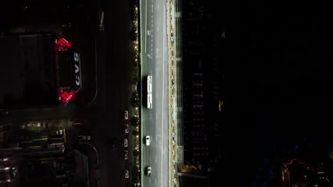 Von-Oben-Aufgenommene-Drohne,-Die-Einem-Bus-Auf-Dem-Beleuchteten-Las-Vegas-Boulevard-Folgt