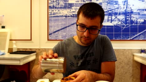 Man-sprinkling-cinnamon-over-delicious-pastei-de-nata,-Portuguese-pastry-for-breakfast