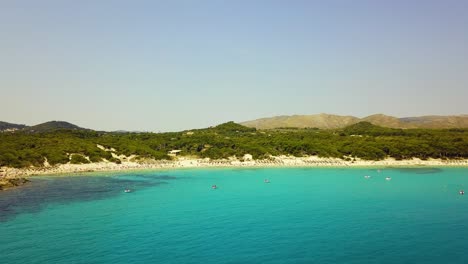 Approaching-drone-shot-of-Cala-Agulla's-stretch-of-long-coastline,-a-sandy-beach-located-in-the-island-of-Mallorca-in-the-Mediterranean-Sea