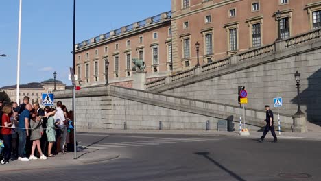Group-of-people-near-Swedish-Royal-Palace-on-sunny-day,-with-police-patrol,-Stockholm