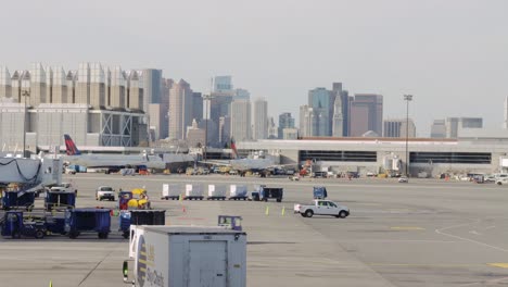 Timelapse-Del-Aeropuerto-De-Boston-Con-El-Horizonte-De-La-Ciudad,-Los-Aviones-Embraer-De-American-Airlines-Salen-Y-Llegan-A-La-Puerta,-Timelapse