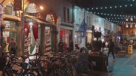 Evening-shopping-scene-on-a-lively-Dublin-street-decorated-with-festive-lights,-bicycles-in-the-foreground