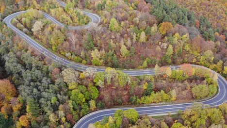 Mountain-road-winding-through-autumn-forest,-passage-in-desolate-wilderness