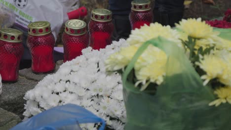 A-close-up-shot-of-candles-and-flowers-on-a-grave,-symbolizing-remembrance-and-reverence-in-a-solemn-moment