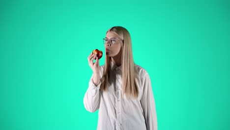 Schöne-Junge-Frau-Genießt-Einen-Roten-Saftigen-Apfel,-Türkisfarbener-Hintergrund,-Studio
