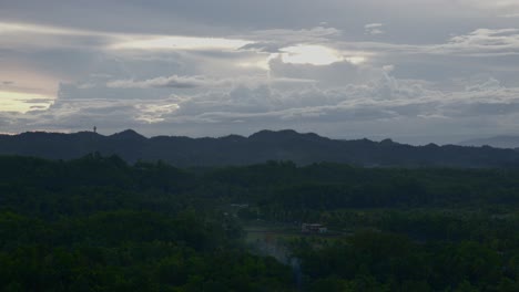 Amanecer-Brumoso-Sobre-Las-Colinas-De-Chocolate-En-Bohol,-Filipinas,-Con-La-Suave-Luz-Del-Sol-Perforando-Las-Nubes