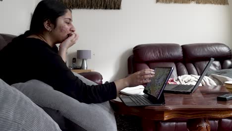 Woman-working-on-laptop-at-home,-daylight,-candid,-side-view,-casual-atmosphere