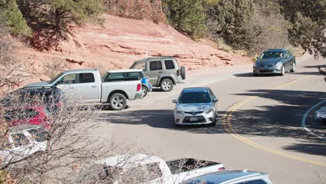 Automóviles-Circulando-Por-La-Carretera-Con-Vehículos-Estacionados-Al-Borde-De-La-Carretera.