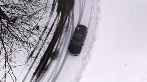 Birdseye-Shot-of-Black-Car-in-Roundabout-in-Winter