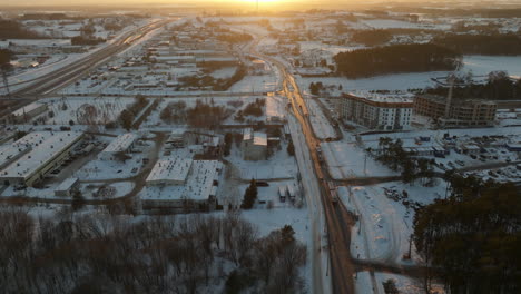 Birds-eye-flight-over-snowy-polish-city-at-sunset-time