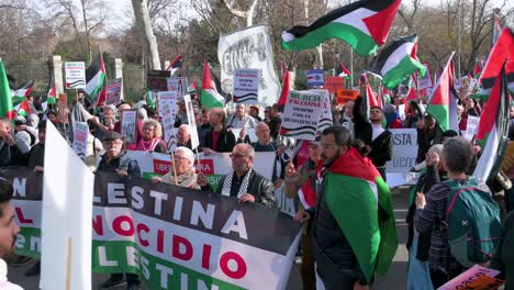 Protesters-hold-a-banner-and-wave-Palestine-flags-during-a-march-in-solidarity-for-Palestine