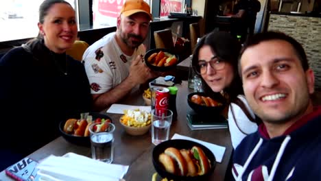 Excited-group-of-friends-eating-hamburger-fast-food-meal,-selfie-vlogger-shot