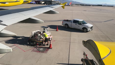 El-Personal-De-Tierra-Comprueba-Las-Líneas-De-Reabastecimiento-De-Combustible-En-La-Pista-Del-Aeropuerto-De-Las-Vegas,-Con-Aviones-Y-Vehículos-A-La-Vista.