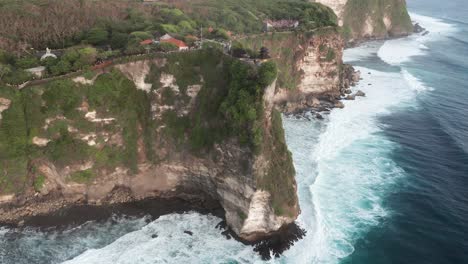Aerial-view-of-beautiful-Uluwatu-Temple-on-high-cliff-with-ocean-waves-in-Bali,-Indonesia
