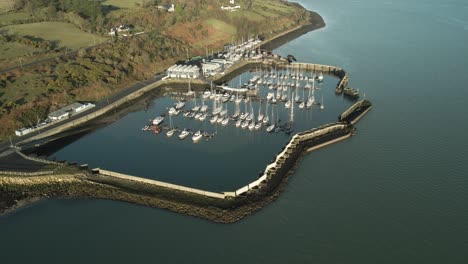 A-serene-marina-with-boats-docked-in-carlingford-lake,-county-louth,-ireland,-on-a-sunny-day,-aerial-view