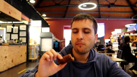 Man-savoring-a-delectable-cod-croquette-at-Beira-Rio-Market,-expressing-approval