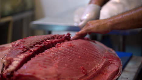 Slow-motion-close-up-of-a-male-chef-cutting-the-side-part-of-a-fresh-blue-fin-tuna-in-half