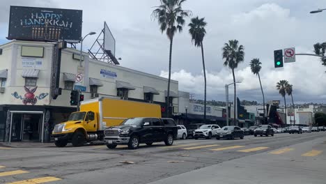 Corner-of-Fairfax-and-Rosewood-with-vehicles-driving-by-in-Los-Angeles,-California-with-video-panning-right-to-left