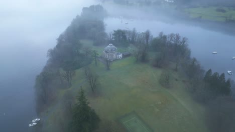 Acercándose-Al-Dron-Y-Descendiendo-Lentamente-Hacia-Una-Residencia-Aislada-En-Una-Isla-En-Medio-Del-Lago-Windermere,-En-El-Reino-Unido