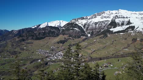 Amden-Weesen-Switzerland-flight-over-trees-reveals-town-at-mountain-base