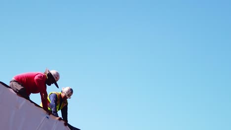 Gimbal-panning-shot-of-a-construction-crew-working-on-the-roof-of-a-modular-house-at-a-building-site-in-West-Los-Angeles,-California