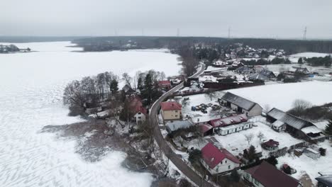 Pueblo-Rural-Polaco-En-Un-Lago-Congelado-En-Invierno,-Campo-Nevado,-Plataforma-Rodante-Aérea