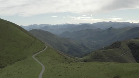 Cars-driving-along-panoramic-road-of-Col-Inharpu-with-mountain-range-in-background,-Basque-Pyrenees,-France