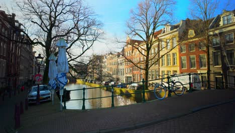 Wunderschöner-Holländischer-Blick-Auf-Grachtenhäuser,-Fahrräder-Und-Wasser-Im-Stadtzentrum-Von-Amsterdam-Im-Sonnenlicht
