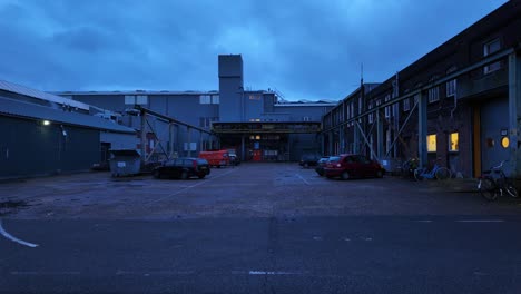 Gloomy-parking-lot-in-between-early-20s-century-industrial-buildings-twilight