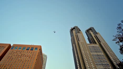 Editorial-footage-showing-typical-upward-looking-view-of-aircraft-flying-over-a-section-of-Shinjuku,-Tokyo,-Japan