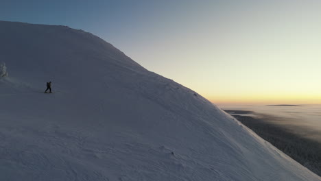 Ein-Freeskier-Klettert-Zum-Gipfel,-Während-Die-Bunte-Sonne-Hinter-Dem-Berg-Aufgeht