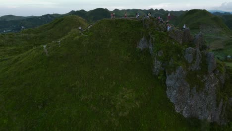 Group-of-hikers-on-Osmena-Peak,-Philippines,-with-lush-greenery,-under-cloudy-skies,-aerial-view