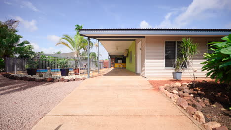 Colourful-Tropical-Home-Driveway-Entry-With-Metal-Floral-Gate-Pattern-Dolly-To-Covered-Outdoor-Area-By-Pool