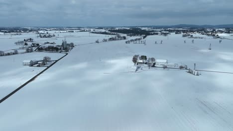 Drone-high-angle-showing-snowy-winter-scenery-with-farmstead