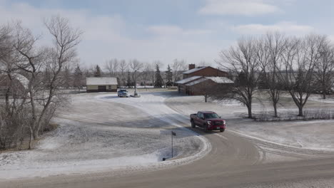 Red-Pickup-Truck-Leaving-Home-on-a-Snowy-Rural-Road